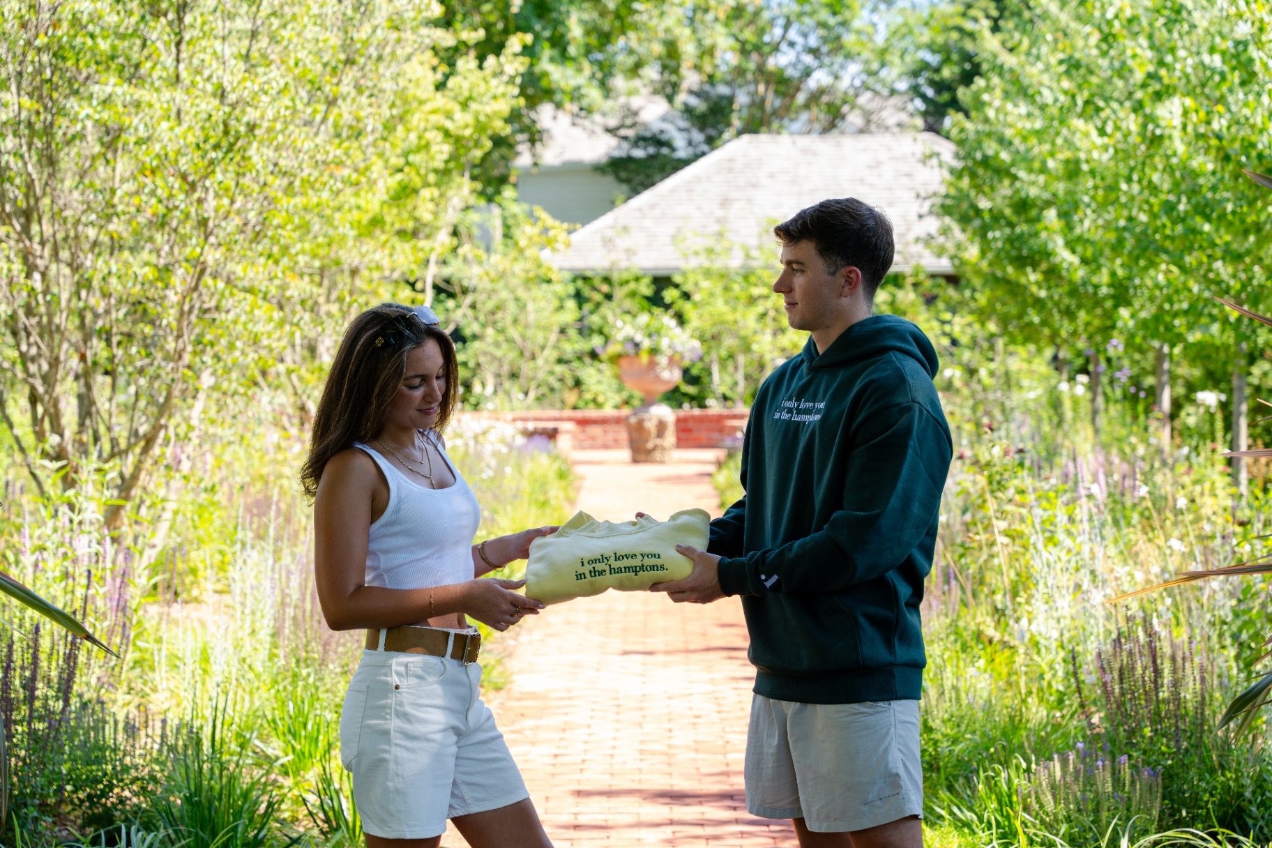 Yellow crewneck passed between two friends in the garden