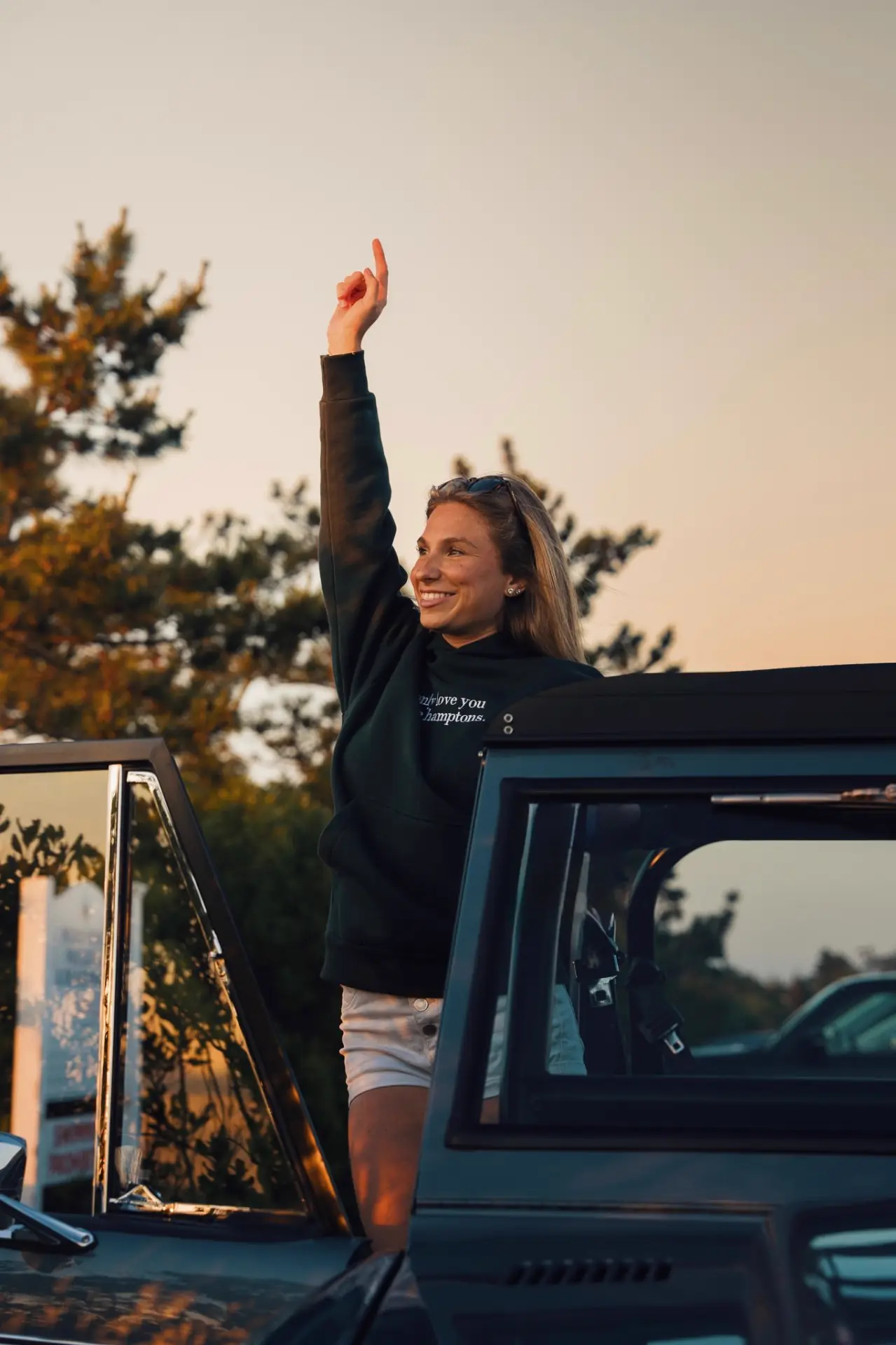 Yellow crewneck, one hand up in the Bronco